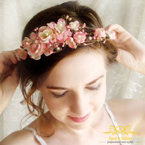 Bờm hoa màu hồng đẹp mắt kết hợp với kiểu tóc uốn xoăn nhẹ 2 bên mái vô cùng phù hợp.